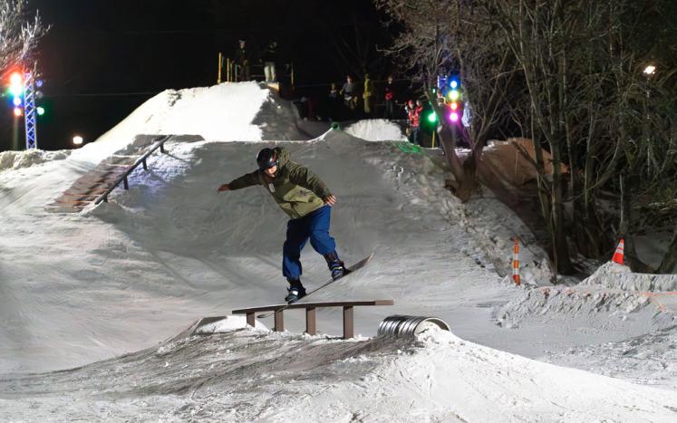 A snowboarder grinds on a rail during the Heikki Lunta Rail Jam event